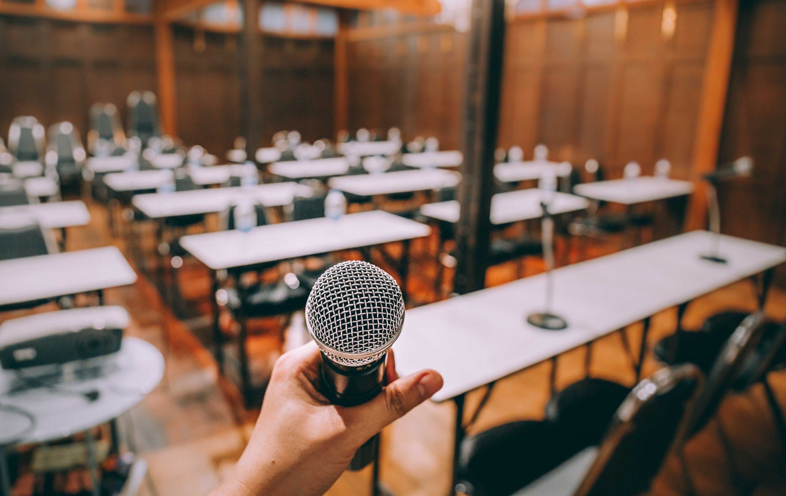 close-up-microphone-with-blurred-people-attending-2022-12-16-06-16-19-utc